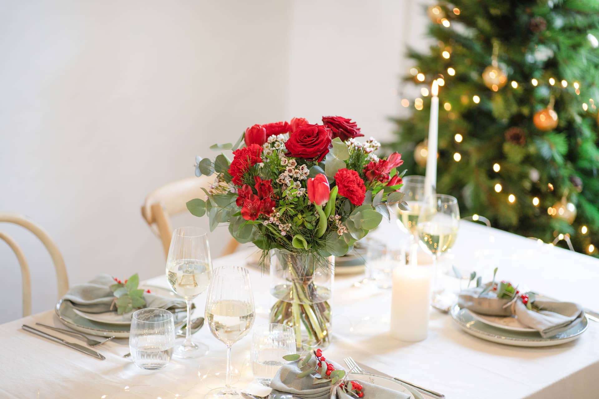 Bouquet de fleurs de Noël posé sur une table devant un sapin de Noël