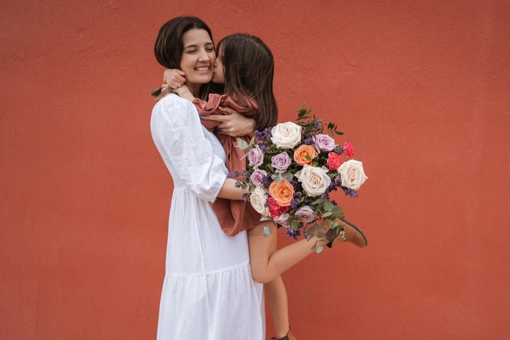 mère et fille dans les bras avec un bouquet de fleurs