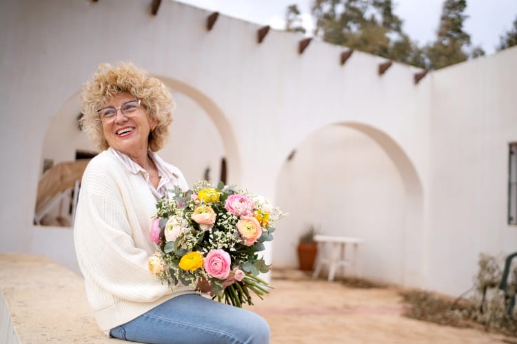 Une mamie tient un grand bouquet de fleurs