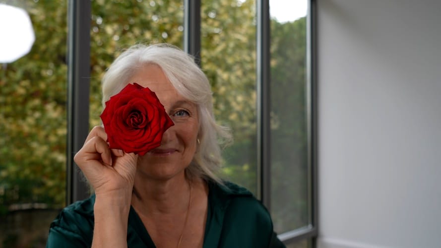 Une grand-mère tient une rose rouge devant son oeil