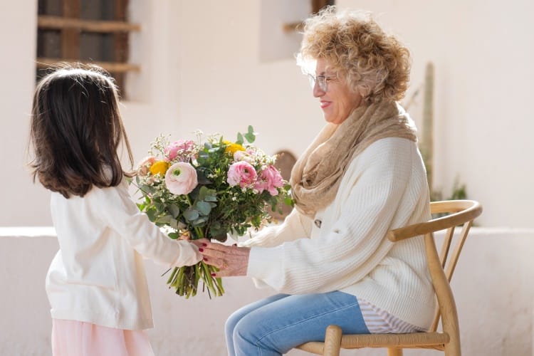 une petite-fille offre un bouquet à sa grand-mère