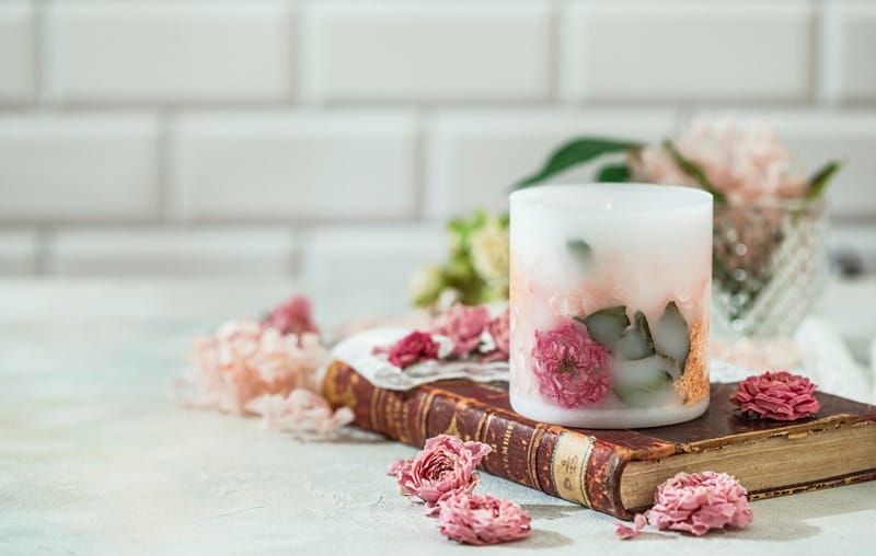 Bougie contenant des pétales de fleurs séchées posée sur un livre