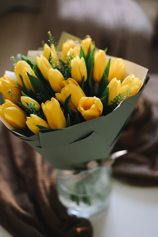Un bouquet de tulipes jaunes dans un vase sans soleil direct