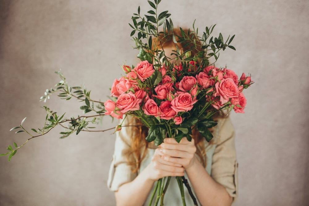 Une femme tient un bouquet devant son visage
