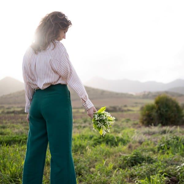 une jeune femme tient des brins de muguet dans un champ