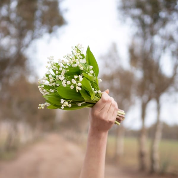 une personne porte un bouquet de muguet