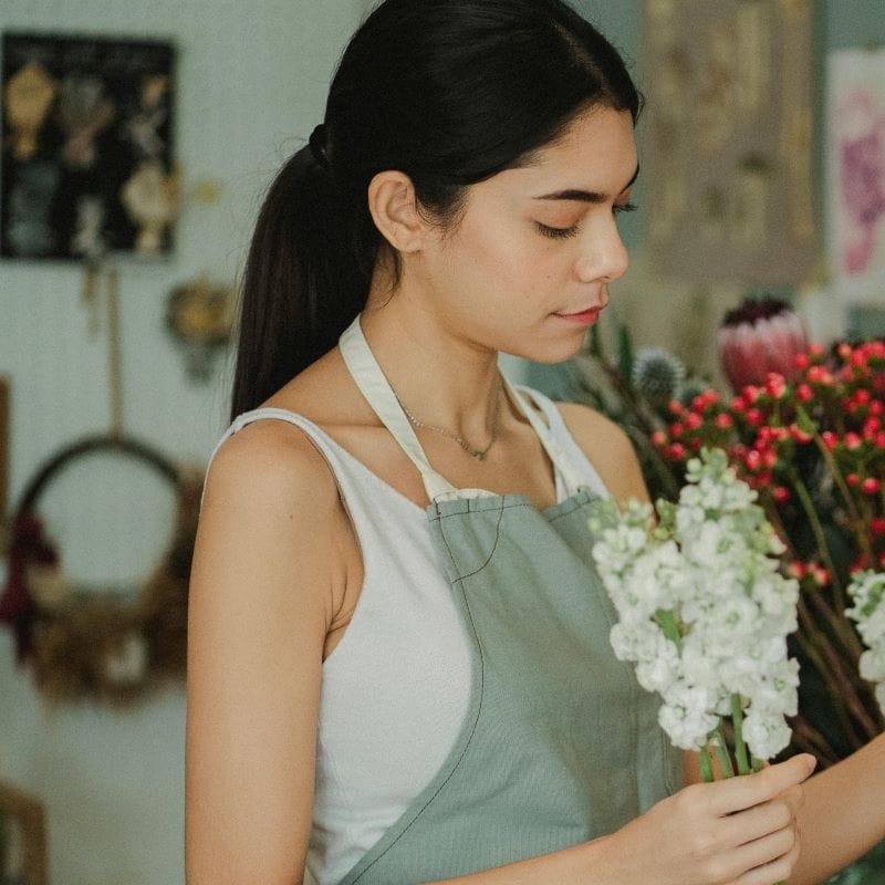 femme en tablier de jardinage avec des fleurs