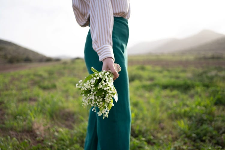 une femme avec un bouquet de muguet dans un champ